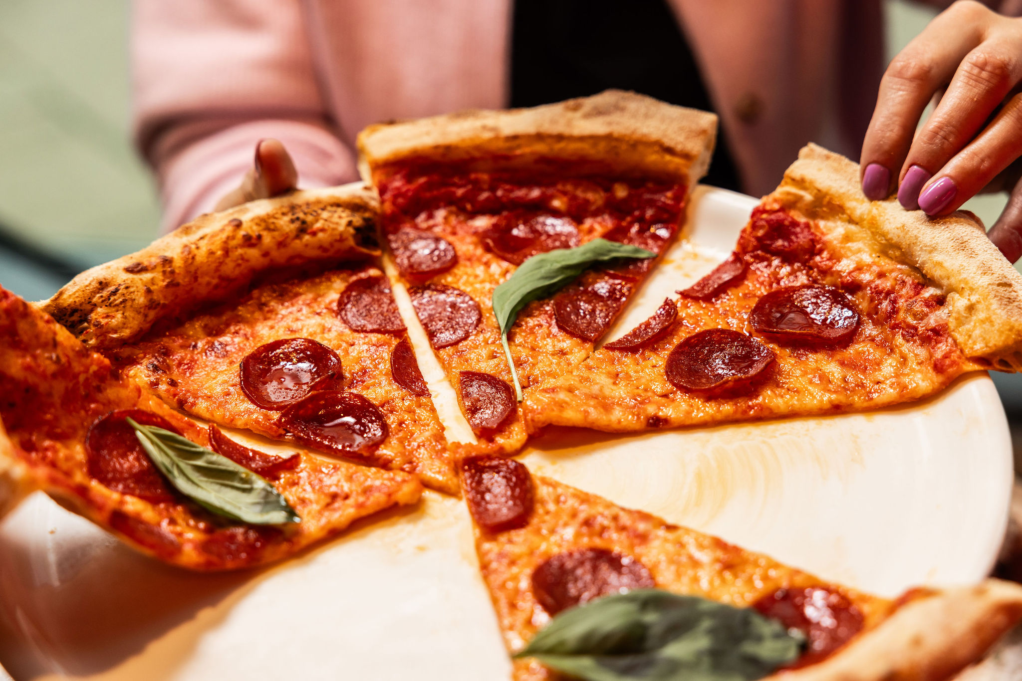 Diner picking up a slice of pepperoni pizza from a sharing plate at Dip Doh Pizza Co.