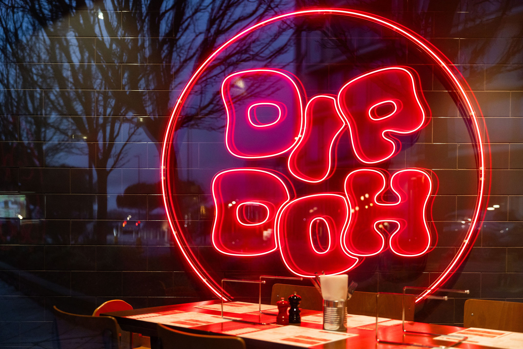Red Dip Doh neon sign glowing above restaurant tables.