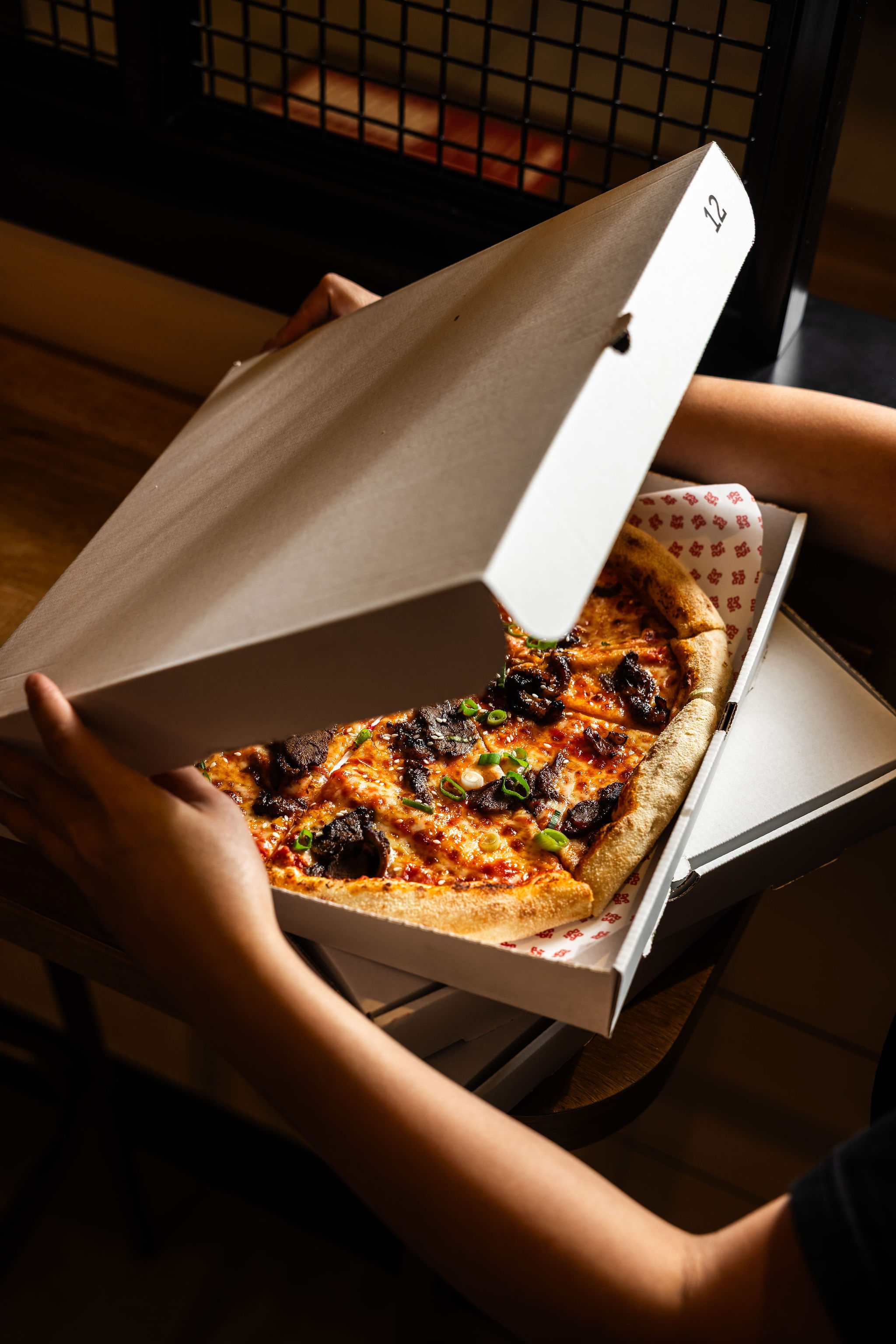 Person prepping a pizza box to package a freshly baked Dip Doh pizza.