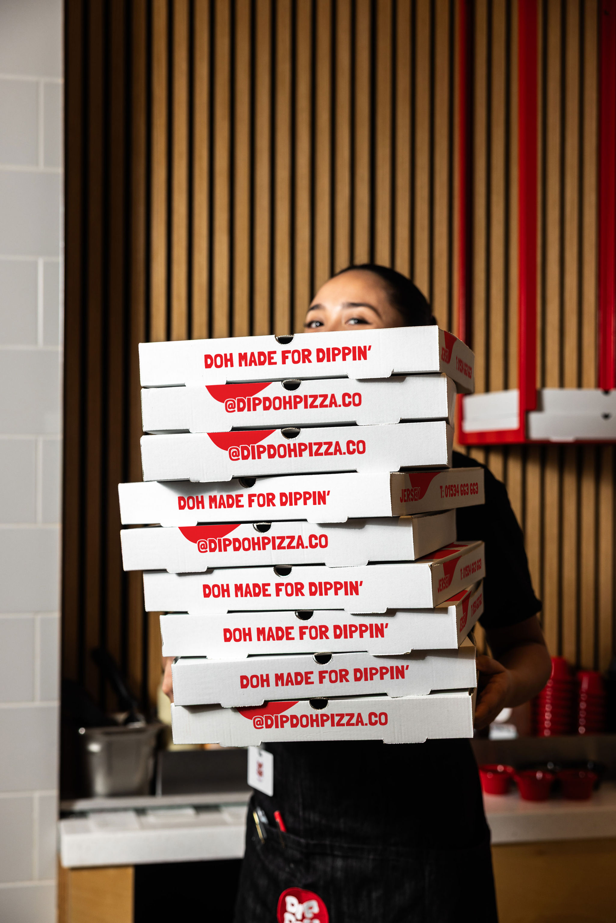 Dip Doh team member carrying a tall stack of pizza boxes.